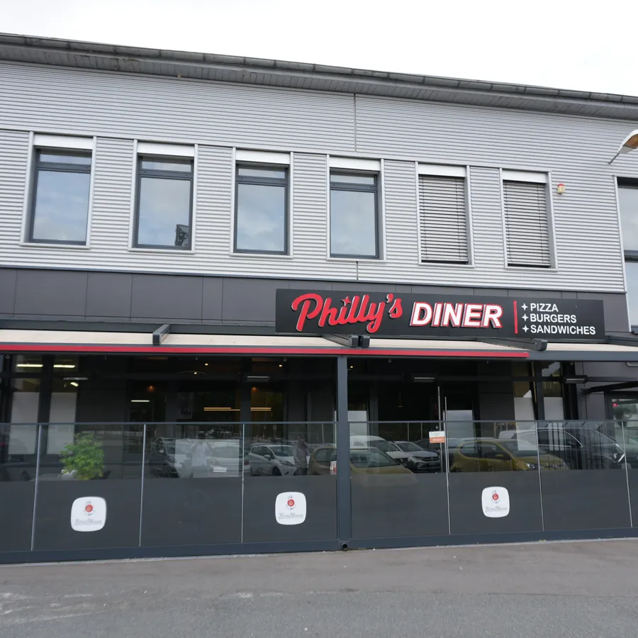 Außenansicht von Philly's Diner mit Terrasse und roter Leuchtschrift